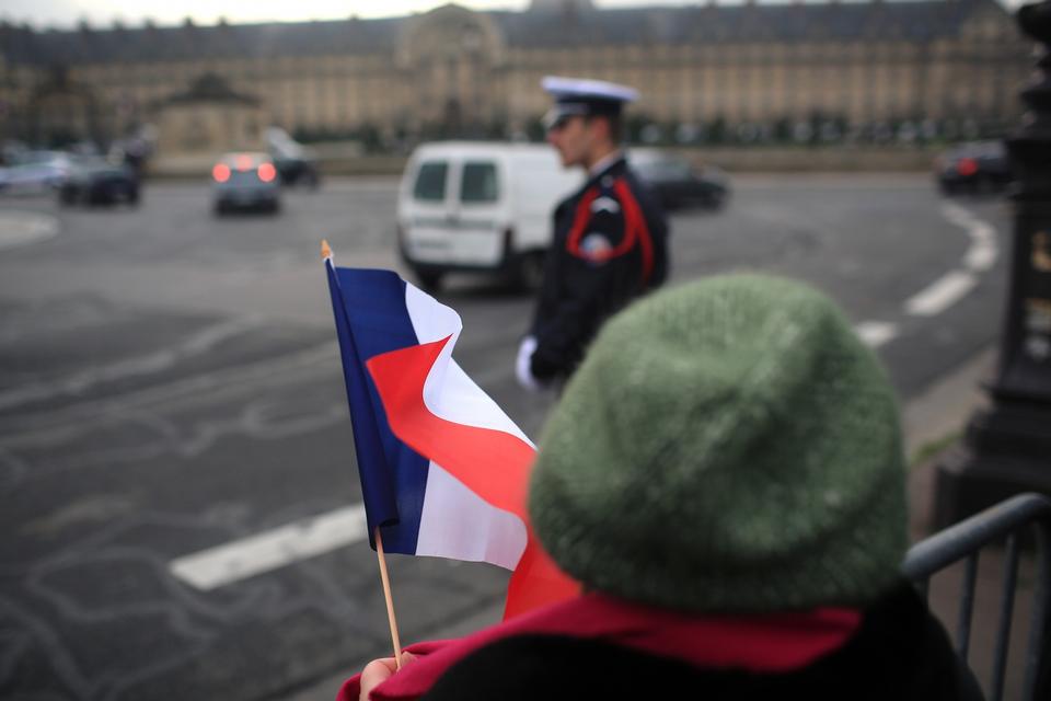 En kvinde er mødt op med det franske flag foran Les Invalides, hvor den officielle ceremoni for at markere massedrabene finder sted. 