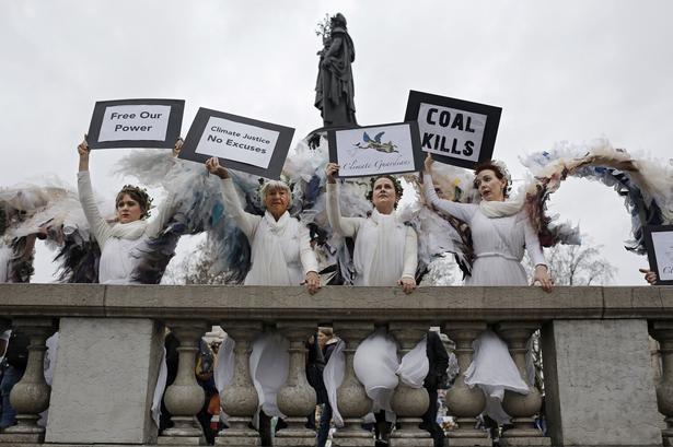 Et andet sted på pladsen står nogle damer i englekostumer som en del af en stille protest arrangeret af ngo'en Avaaz. 
