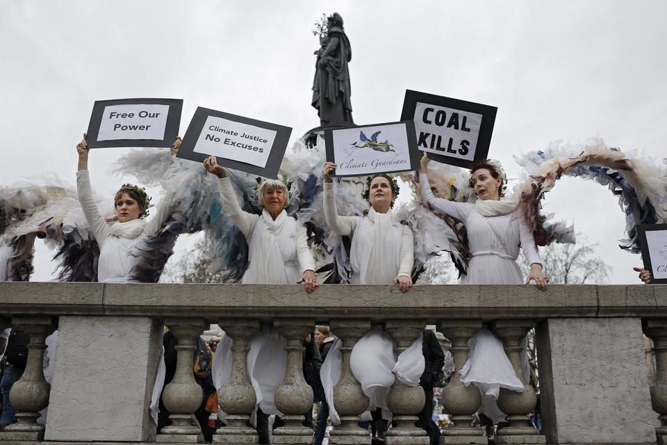 Et andet sted på pladsen står nogle damer i englekostumer som en del af en stille protest arrangeret af ngo'en Avaaz. 