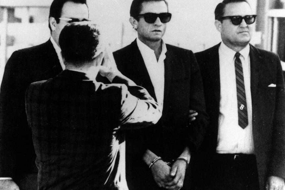 Cash er bl.a. kendt for sangen 'Folsom Prison Blues' og live-pladen 'At Folsom Prison' optaget i det amerikanske fængsel Folsom. Selv sad han aldrig i fængsel, men tilbragte dog 9 dage i arresten. På billedet fra 1965 er han netop blevet anholdt ved den mexicanske grænse med guitar-tasken fuld af piller. Han slap med en betinget dom og en bøde på $1.500. 