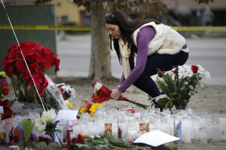 Sorg. En kvinde placerer blomster foran det center i San Bernardino, hvor 14 personer blev dræbt af et bevæbnet ægtepar. Nu siger Ilslamisk Stat, at terrorbevægelsen stod bag skudangrebet. 