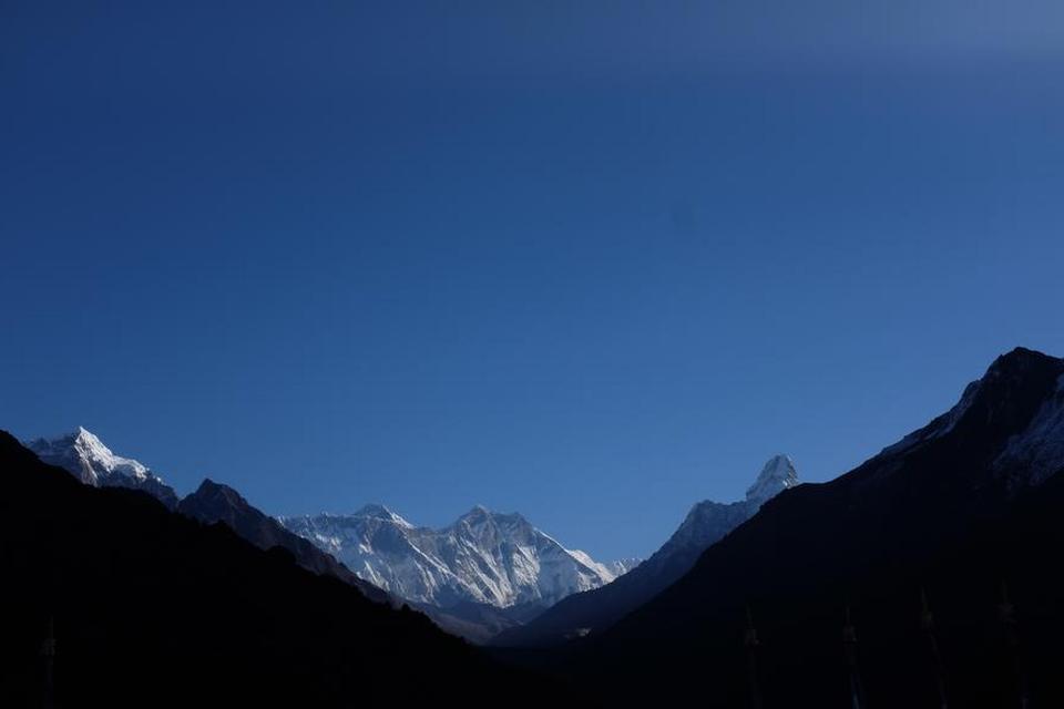 TAG. Lidt til venstre for midten af billedet stikker en top frem i baggrunden. Den ser ikke ud af meget. Men det er Mount Everest, verdens højeste bjerg med en top i 8.850 meter over havets overflade.