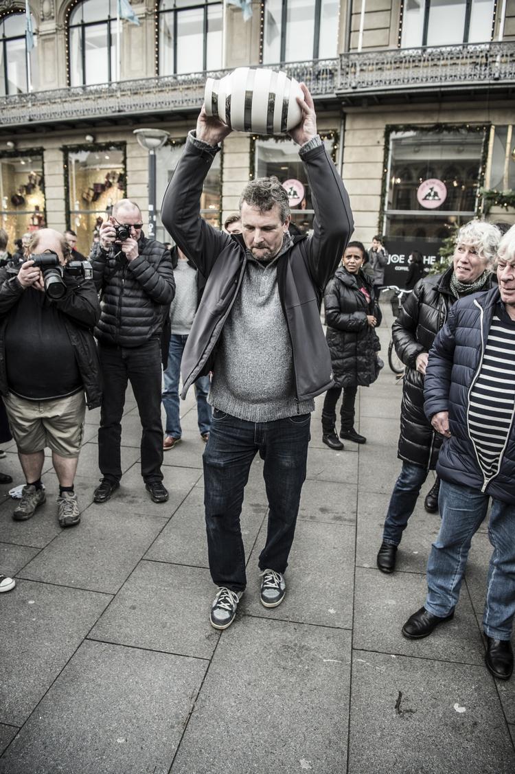 Klir. En kødrand af mennesker og pressefolk stod klar, da seks Kähler-vaser i dag blev smadret på Kongens Nytorv i København. »Har vi i virkeligheden brug for de ting? De virkelige værdier i tilværelsen er jo ikke en samling af Kählervaser«, fortæller Peter Holst Eriksen (billedet). 