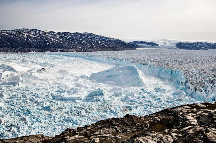 Helheim. Sydøstgrønlands største gletsjer er en af de vigtigste kanaler fra indlandsisen ud til havet. Her ses den seks kilometer brede gletsjer, mens den kælver i 2013. Den vigtigste del af billedet ligger dog i bjergene i baggrunden, hvor linjen mellem lysere og mørkere fjeld viser isens udbredelse under den lille istid frem til omtrent 1850. Arkivfoto: Nicolaj Krog Larsen, Aarhus Universitet 