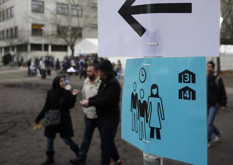 Flygtninge. Migranter ved et skilt i Berlin, der viser asylansøgere vej til et lokalt velkomstcenter. 