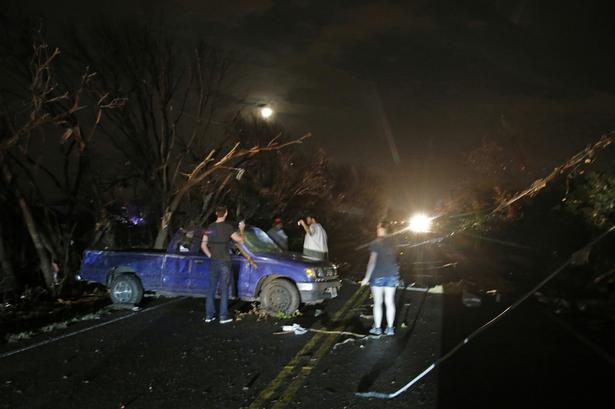 Flere træer og el-ledninger måtte bukke under for tornadovejret. Her er det folk nær Rowlett, der undersøger en smadret bil. Føreren af denne bil kom ikke noget til. 