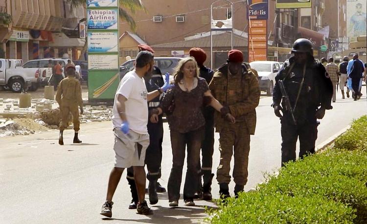ANGREB. En kvinde føres i sikkerhed, efter terrorister i går åbnede ild på et luksushotel i Burkina Fasos hovedstad og en nærliggende café i byen. Foto: AP 