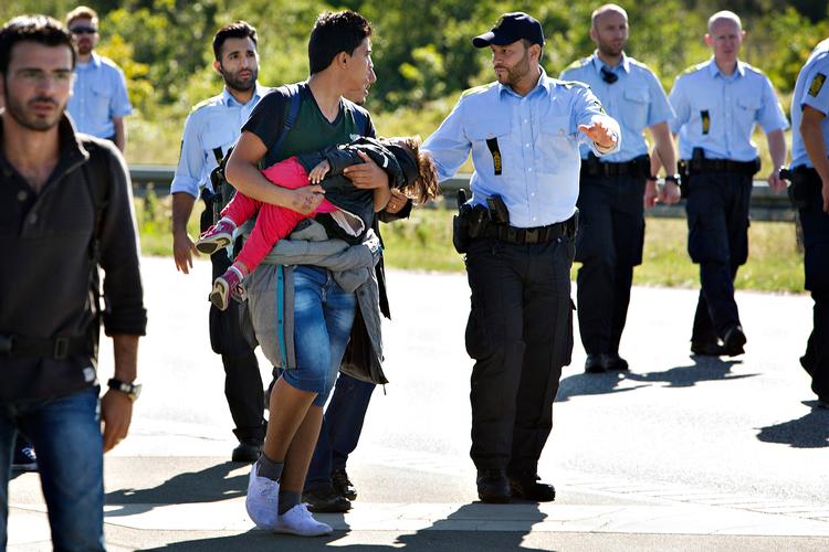 Martin Lehmann fortæller: Kl. 15 slutter jeg mig til gruppen af flygtninge og politi på den sønderjyske motorvej. Jeg præsenterer mig for politiet og fremviser pressekort. 