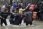 MIGRANTRUTE. En aktivist giver en hånd til en kvinde på vej over grænsefloden. 
