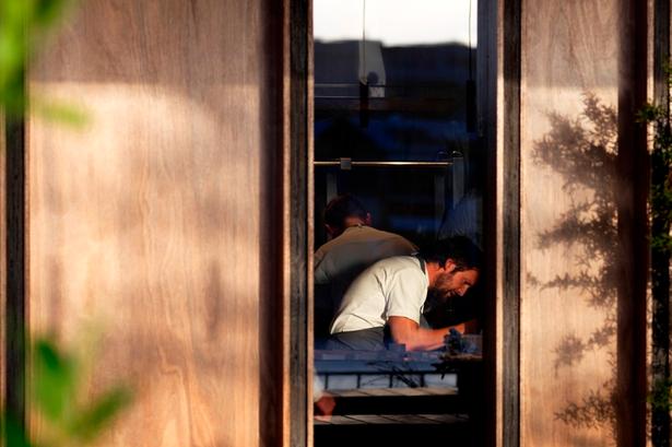 Tilbage ved restauranten. Michael Larsen bringer dagens høst tilbage til Nomas pop up-restaurant. Her ses René Redzepi gennem vinduet. 