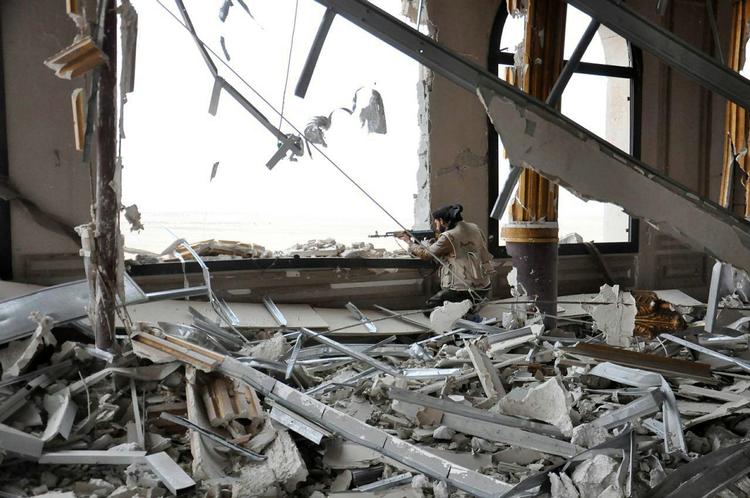 Kampe. Foto frigivet 24. marts af det syriske nyhedsbureau SANA viser en soldat fra regerringsstyrkern, der søger dækning i et beskadet palads på grænsen til Palmyra. 