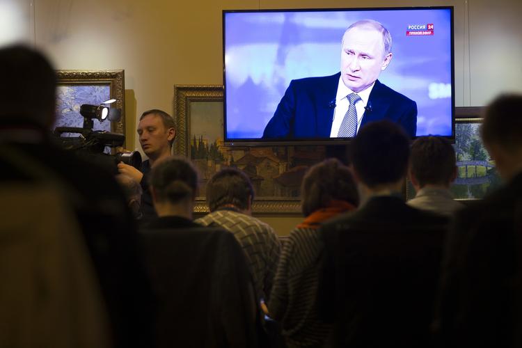 Journalister ser på tv, mens Putin svarer på spørgsmål fra folket. 