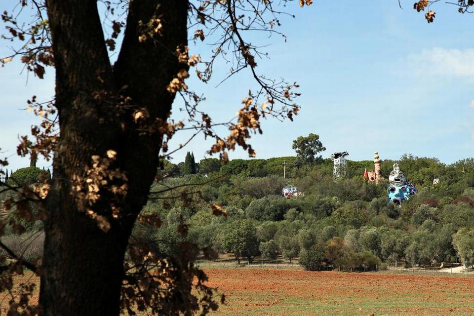 SKUE. Kører man fra Rom langs kysten mod Monte Argentario og Grosseto, kan man, lige når man er kørt ind i Toscana, skimte nogle store farvestrålende strukturer, der stikker op midt i et skovbælte.