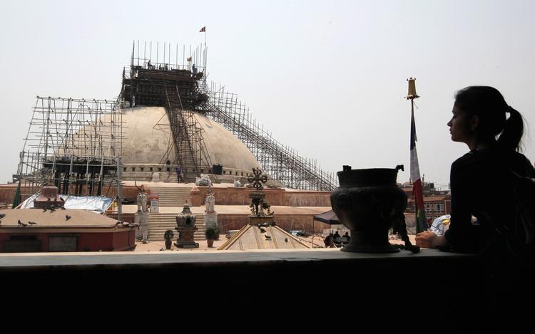 Genopbygning. En nepalesisk kvinde betragter genopførelsen af  Boudhanath Stupa, der blev beskadiget i sidste års jordskælv. Landets premierminister har netop meddelt, at man påbegynder genopbygningen af en række ødelagte kulturarvssteder i Kathmandu. Foto: Niranjan Shrestha/AP 