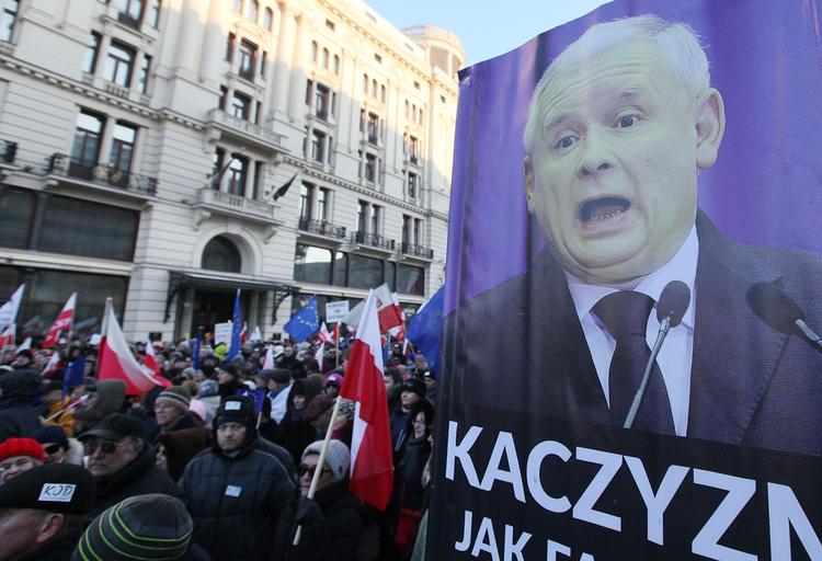 Protest. I januar demonstrerede polske demokratibevægelser i Warszawa mod lovændringer fra regeringspartiet PiS, ledet af Jaroslaw Kaczynski (plakaten). Nu angriber EU den polske regerings indgreb i domstolenes uafhængighed. 