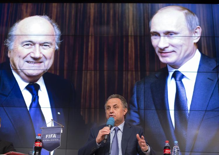 Belastet. Vitalij Mutko - den russiske sportsminister, der har taler mellem billeder af skandaliserede Sepp Blatter og præsident Putin - er en af de mest udskældte ledere i Uefa og Fifa, da han både er mistænkt for korruption og at styre et dopingregime. Arkivfoto: Alexander Zemlianichenko/AP 