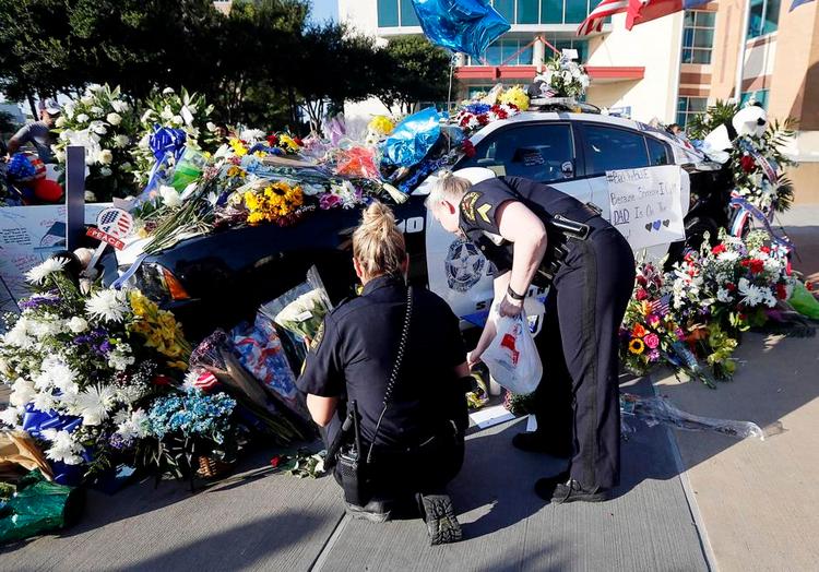 Sorg. Politi lægger blomster og lys ved en bil, der er blevet til mindesmærke for de fem dræbte betjente. 