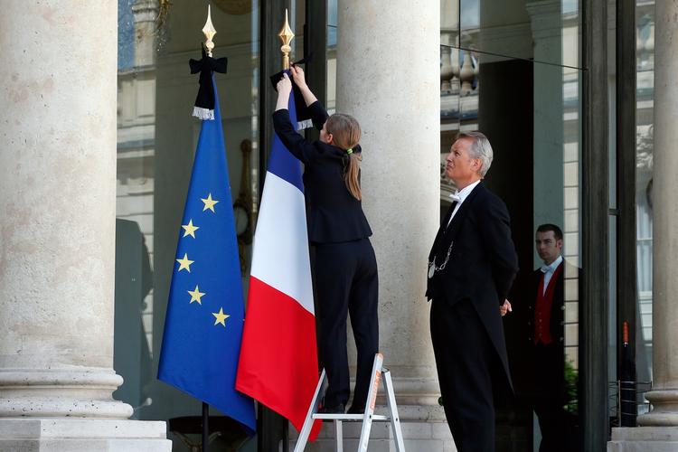 sørgebånd. En ansat ved Elysee præsident-paladset sætter sørgebånd på flagene, efter at Frankrigs præsident har deklareret tre dages landesorg. 