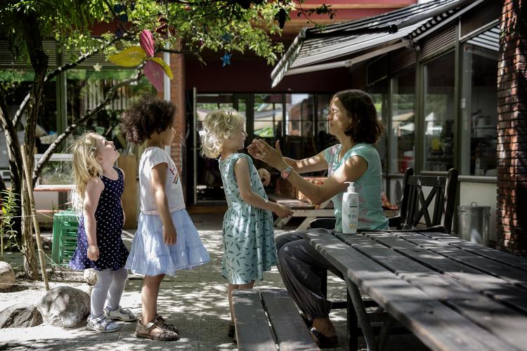 Børneliv. Lykke får solcreme på af pædagogen Vibeke,  imens Amina og Sofia står pænt i kø. 