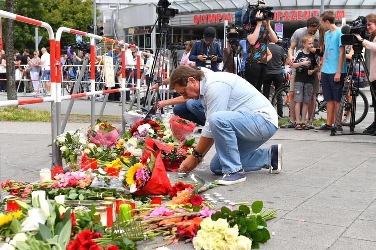 Sorg. En mand lægger blomster foran mindested for de dræbte ved fredagens skudattentat. 