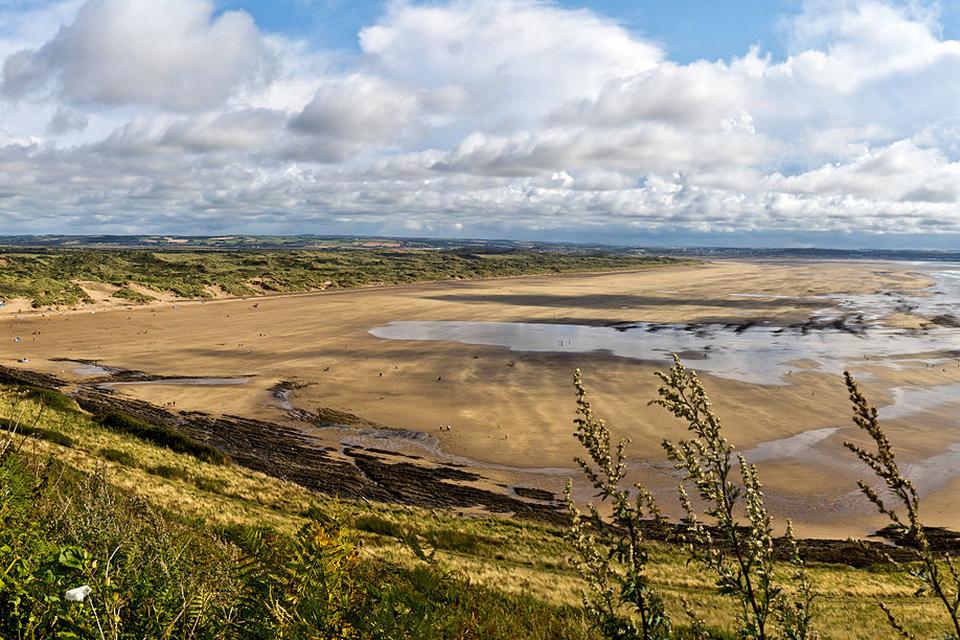 Saunton Sands. Her er vi på nordkysten af Devon, og stranden er et paradis for drageflyvere. Fra tid til anden spærres stranden af på grund af nogle endnu større flyvende objekter. Det britiske flyvevåben træner nemlig start og landing på sandstrande med store Hercules C-130-fragtfly. I den periode må man søge tilflugt i de mange sandklitter. 