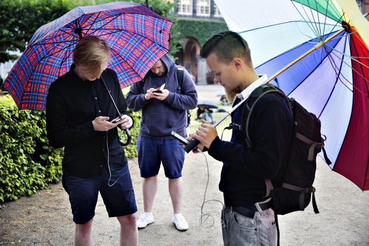 STEMNING. I bibliotekshaven er stemningen upåklagelig - også selv om det begynder at trække op til regn. Almindeligvis ville de fleste hurtigt traske indendøre. Men ikke her. I stedet tager de mange Pokémon-jægere regntøjet på og slår paraplyerne op. 
