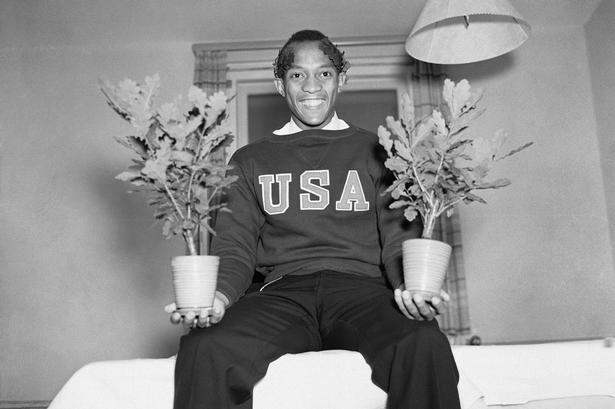Sejrsherre. Jesse Owens efter sin tilbagevenden til staterne med sine præmier, olympisk eg, som blev givet for sejrene i hhv. løb og spring. 