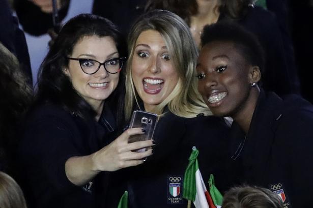 te italienske atleter tager en selfie under nationens indmarch på det store stadion. 