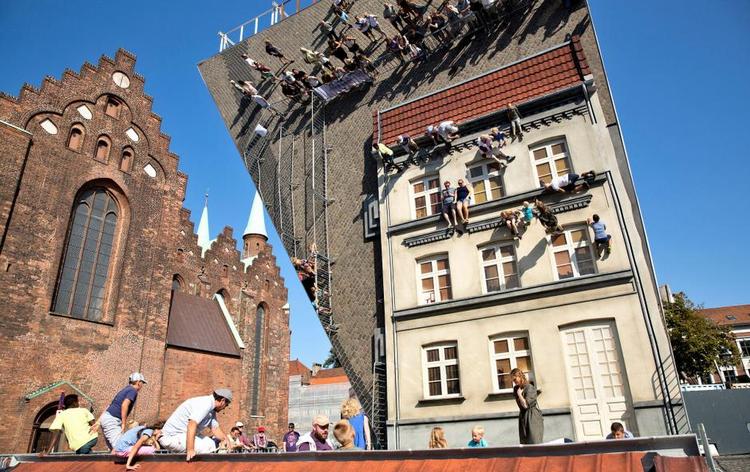 SPEJLING. De dødsforagtende klatrere ligger i virkeligheden fladt ned. Argentinske Leandro Erlich har under Aarhus Festuge rejst sit gigantiske spejl af et synsbedrag. Festugens tema var ’Upside Down’. Foto: Martin Dam Kristensen 