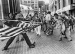 ANGREB. Under en demonstration ved Boston City Hall i april 1976 mod skolebus- kørsler går den hvide demonstrant Joseph Rakes til angreb på den sorte Theodore Landsmark med det amerikanske flag. Foto: Stanley J. Forman/AP, fra bogen 