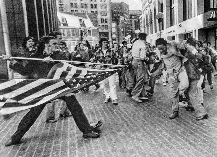 ANGREB. Under en demonstration ved Boston City Hall i april 1976 mod skolebus- kørsler går den hvide demonstrant Joseph Rakes til angreb på den sorte Theodore Landsmark med det amerikanske flag. Foto: Stanley J. Forman/AP, fra bogen 
