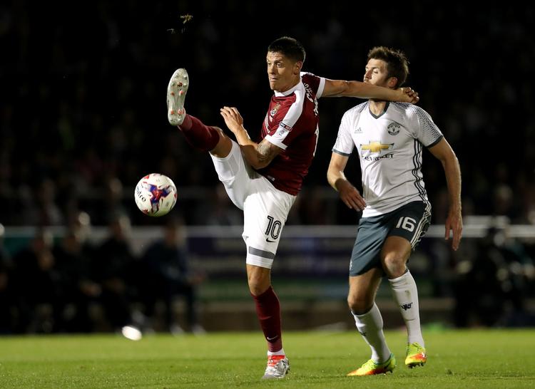 MÅLMAGERE. Michael Carrick (th.), der bragte Manchester United i spidsen, og Alex Revell, der udlignede for Northampton Town, i duel om bolden på Sixfields Stadium. 