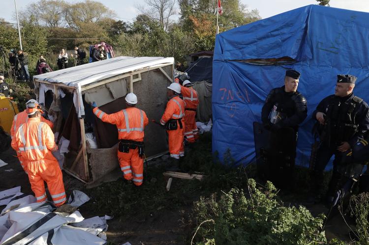 RYDNING. Arbejdere fjerner slumlejren under politibevogtning. Myndighederne har sendt et stort antal betjente til området for at gribe ind ved eventuelle optøjer, men foreløbig er operationen gået nogenlunde stille og roligt. 