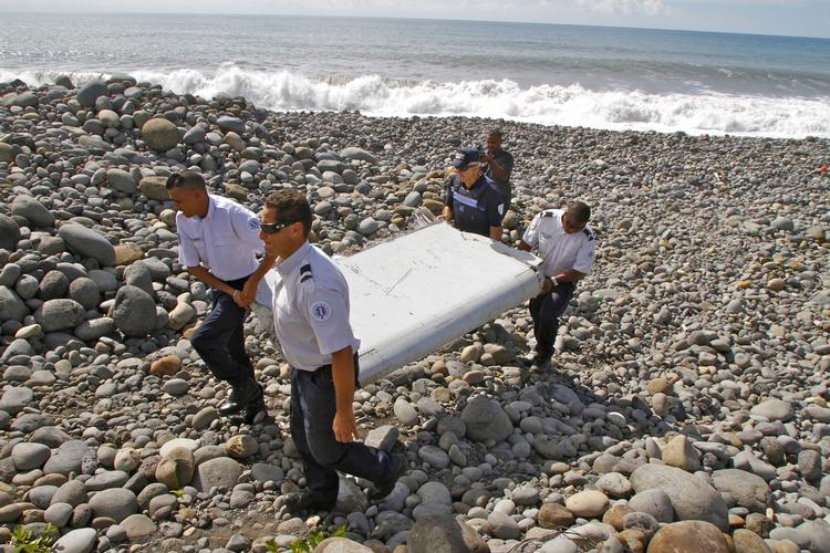 Bevis. Politifolk bærer et stykke af en vinge ved Mauritius' kyst. Det blev senere fastslået, at vragdelen stammede fra det forsvundne fly MH370. 