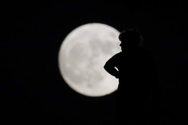 En kvinde står i silhouet mod den flotte måne over La Habra i Californien. 