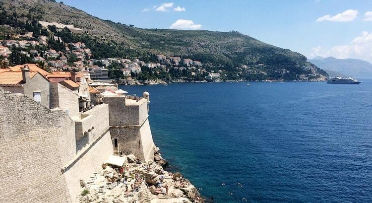 SOLBADNING. Lokale og turister soler sig på klipperne på ydersiden af borgmuren, der omkranser den kroatiske by Dubrovnik. 