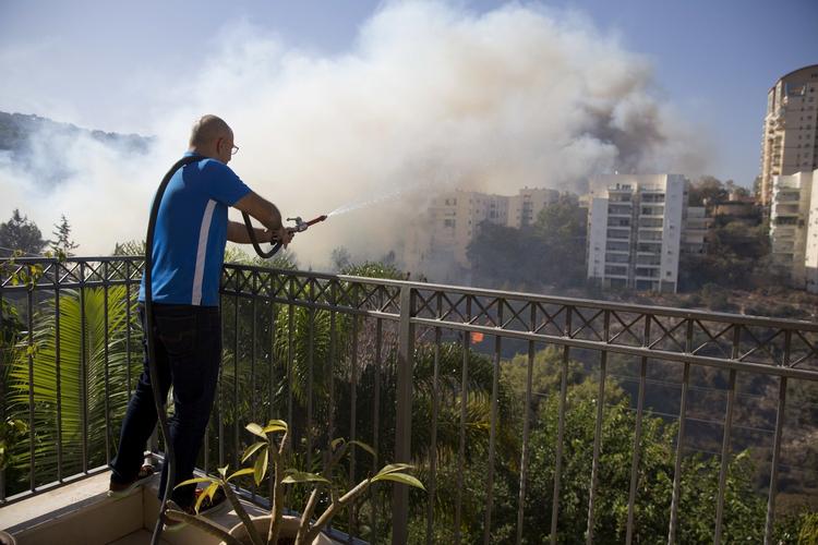 brandmand. En beboer i  Haifa gør sit eget spinkle forsøg på at bekæmpe en brand foran sit hjem. 
