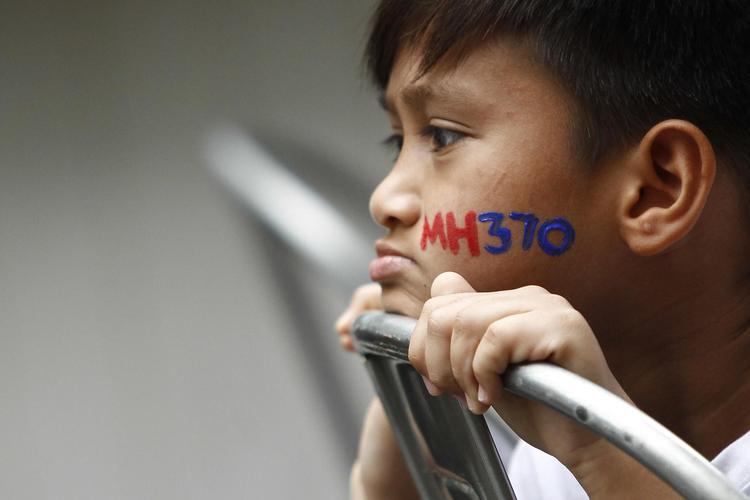 En malaysisk dreng med MH370 malet på kinden ser på under en mindehøjtidelighed for de mennesker, som forsvandt med det malaysiske fly, der var på vej fra Kuala Lumpur i Malaysia og til Beijing i Kina lørdag 8. marts 2014. 