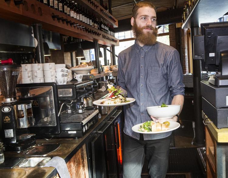 Seattle i det nordvestlige USA har en rigt varieret madscene. En tjener på Melrose Market bærer her retterne ind til gæsterne.  