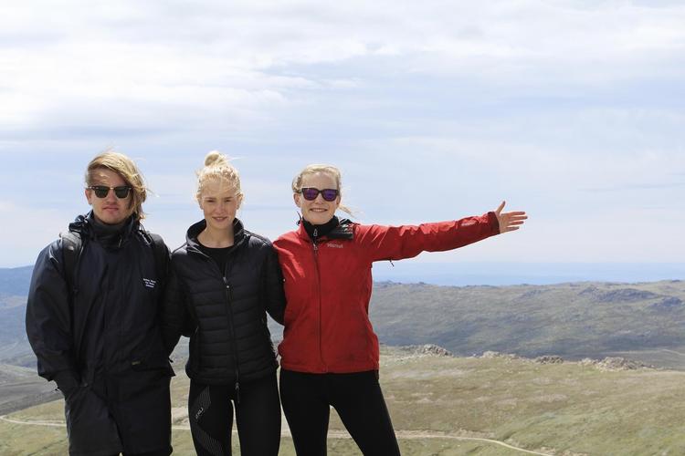På toppen af Mount Kosciuszko er blæsten ekstrem. Det gælder om at holde fast i hinanden, så man ikke vælter omkuld, mens fotografen tager et hurtigt billede. 
