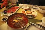 Den nordkoreanske menu består af kimchi, kolde nudler i en chilisuppe, dumplings og et fad med rå laks. 