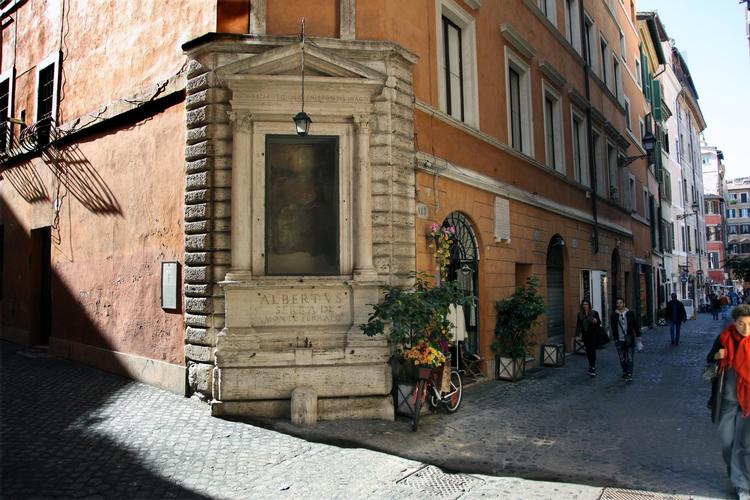 På hjørnet af Viccolo Domizio finder vi et religiøst maleri med Jomfru Maria og Jesus, ’Jomfruens kroning’, malet af Perin del Vaga (1501-1547) og opsat på huset her i 1523 af kardinal Alberto Serra del Monferrato, som døde i Castel S. Angelo i 1527. Guido Bruschini, ejeren af antikvitetsbutikken Liberty spejder efter kunder i den gamle gade. Søren Rud