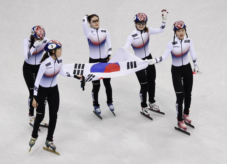 Stolte sydkoreanske kvinder skøjter flaget rundt efter guld i 3.000 meter stafet. Morry Gash/AP